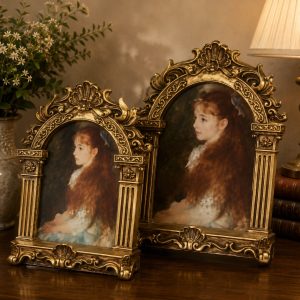 Ornate antique gold picture frames with classic portrait artwork displayed on a wooden table in an elegant vintage interior