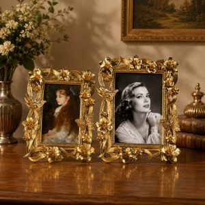 Ornate gold floral frames with flower and butterfly details displayed on a wooden table in a vintage luxury interior